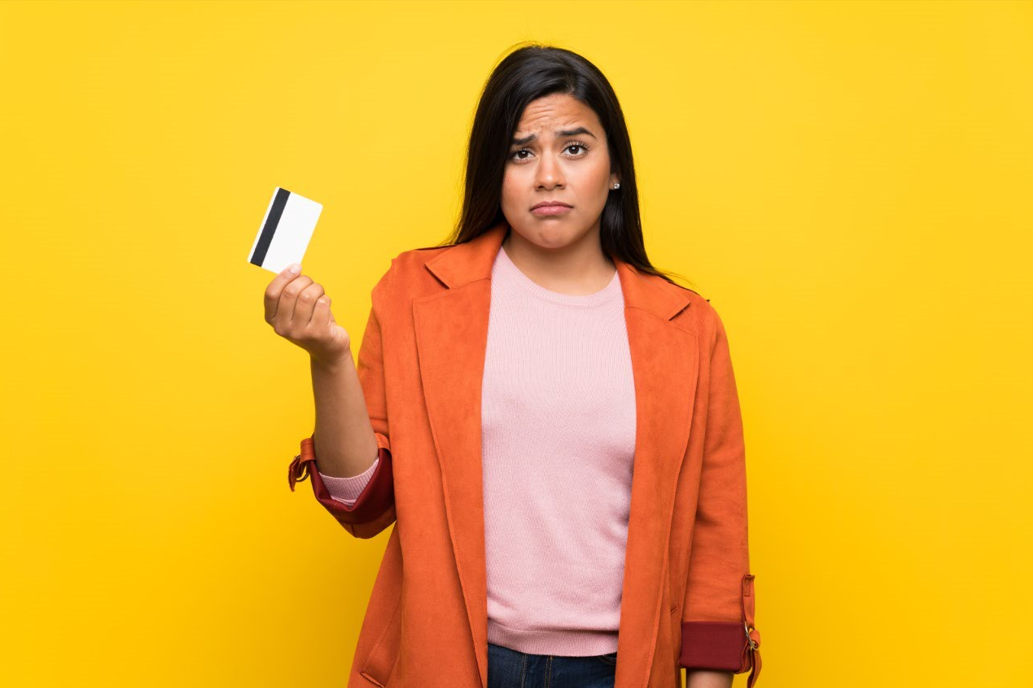 Femme qui fait la moue, tenant une carte bleue entre ses mains